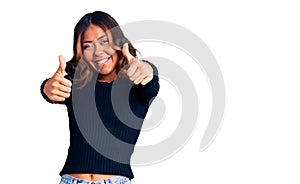 Young beautiful mixed race woman wearing casual clothes approving doing positive gesture with hand, thumbs up smiling and happy