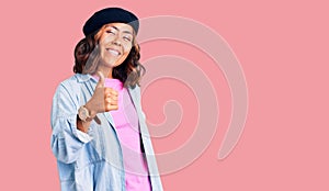 Young beautiful mixed race woman wearing french look with beret doing happy thumbs up gesture with hand