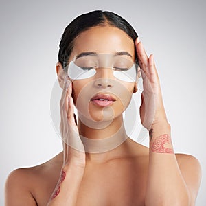 A young beautiful mixed race woman wearing under eye patches. Hispanic model with glowing skin using hydrating treatment