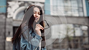 Young beautiful model in the city. Beautiful girl holds sunglasses in hand close-up portrait of a young sexy girl hipster