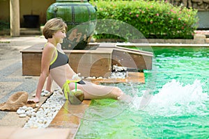 Young beautiful model teenage girl having fun in swimming pool during her vacation trip to tropical Asia