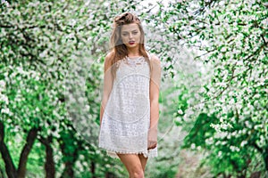 Young beautiful model in white dress in the summer garden