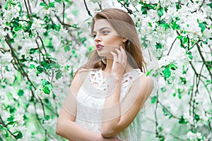 Young beautiful model in white dress in the summer garden