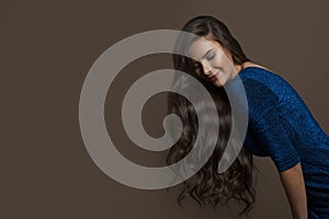 Young beautiful model woman with healthy long curly hairstyle on brown background