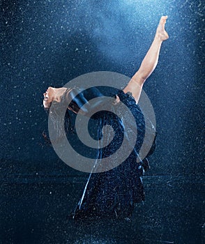 The young beautiful modern dancer dancing under water drops