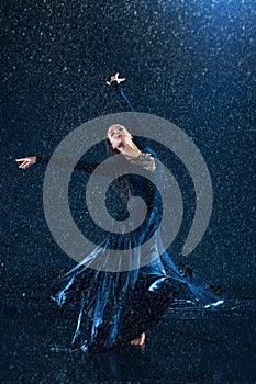 The young beautiful modern dancer dancing under water drops