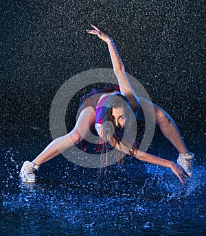 The young beautiful modern dancer dancing under water drops