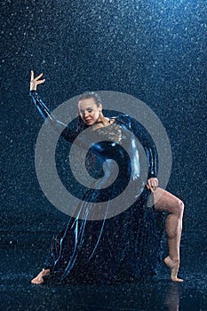 The young beautiful modern dancer dancing under water drops