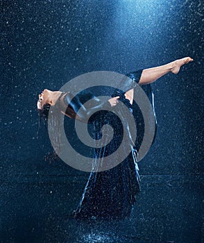 The young beautiful modern dancer dancing under water drops