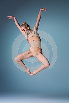 Young beautiful modern style dancer jumping on a studio background
