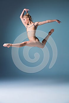 Young beautiful modern style dancer jumping on a studio background