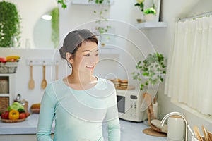 Young beautiful modern woman stands near table on kitchen at home