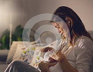 Young beautiful mother, breastfeeding her newborn baby boy at ni