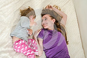 Young beautiful mother and daughter baby girl lying on the bed after waking up in the morning and sip, rested happy family