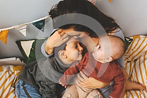 Joven hermoso madre su sobre el una cama cercanamente su un hijo a pequeno besos su frente 