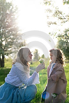 A young beautiful mother and her little daughter are picking flowers