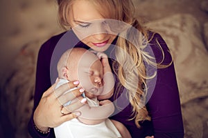 Young beautiful mother holding sleeping newborn baby on hands in