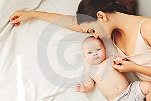 Young beautiful mother lies  the baby on the bed, gently kisses, sleeping together