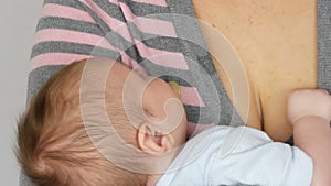 Young beautiful mother with long dark hair is holding a newborn infant baby of two months on white background in studio
