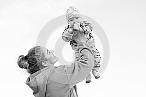 Young beautiful mother plays with her child outdoor. woman hugging her kid against the sea.