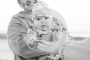 Young beautiful mother plays with her child outdoor. woman hugging her kid against the sea.