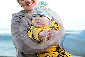 Young beautiful mother plays with her child outdoor. woman hugging her kid against the sea.