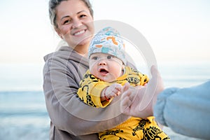 Young beautiful mother plays with her child outdoor. woman hugging her kid against the sea.