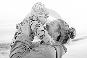 Young beautiful mother plays with her child outdoor. woman hugging her kid against the sea.