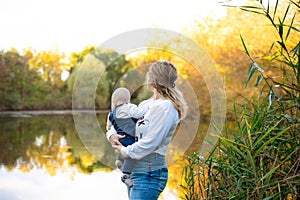 Young beautiful mother plays with her child outdoor. woman hugging her kid against the sea. Happy mother's day.