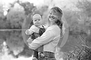 Young beautiful mother plays with her child outdoor. woman hugging her kid against the sea. Happy mother's day.