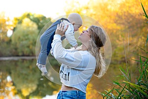 Young beautiful mother plays with her child outdoor. woman hugging her kid against the sea. Happy mother's day.