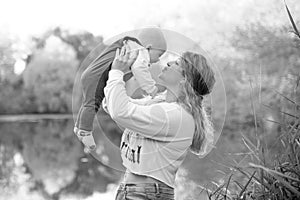 Young beautiful mother plays with her child outdoor. woman hugging her kid against the sea. Happy mother's day.