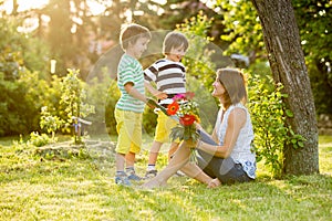 Young beautiful mother, sitting in a garden, little boys, her so