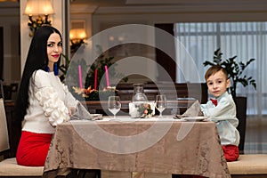 Young beautiful mother with son are sitting in restaurant