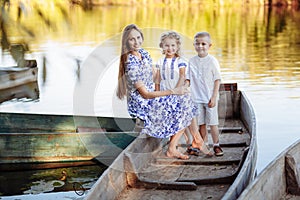 young beautiful mother spending time together with children in boat on lake at park. mothers day. womens day.