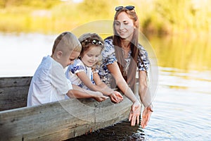 young beautiful mother spending time together with children in boat on lake at park. mothers day. womens day. son and