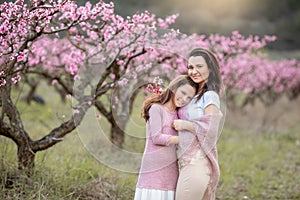Young Beautiful Mother at Spring, Pink Blooming Tree at the Background.