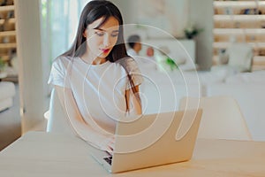 Young beautiful mother works on laptop while her husband looks after baby