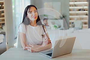 Young beautiful mother works on laptop while her husband looks after baby