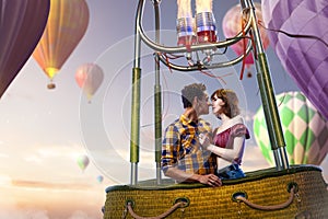 Young beautiful multiethnic couple kissing in the hot air balloon.