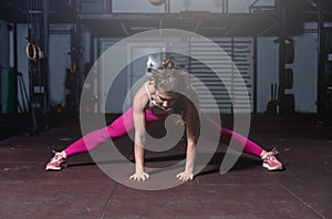 Young beautiful muscular attractive fit girl stretch her hand and body muscles after heavy hardcore cross workout training in the