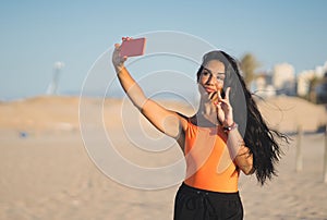 Young beautiful Muslim girl taking a selfie on the beach.