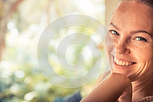 Young beautiful happy smiling tanned woman looking at camera portrait sunny day with copy space during tropical summer holidays
