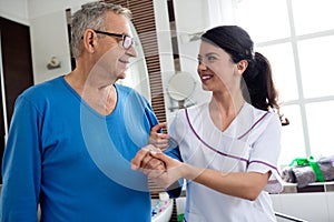 Young beautiful nurse helps to senior man at bathroom