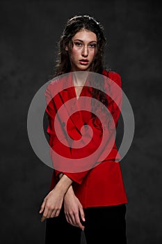 A young beautiful oriental woman with long black hair in a red jacket against a black background. The fashion model