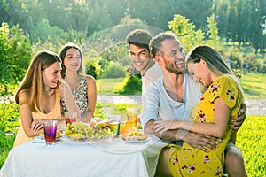 Young beautiful people having a joyful picnic in park