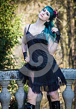 Young beautiful pin up glamour girl with green color hair, high boots on old stone vintage balcony