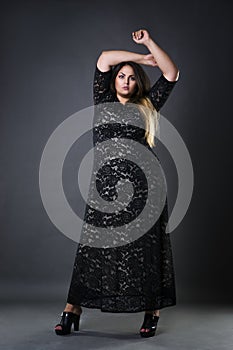 Young beautiful plus size model in black dres, xxl woman on gray studio background