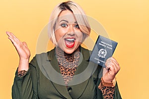 Young beautiful plus size tourist woman holding Italy Itaian passport over yellow background celebrating achievement with happy