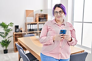 Young beautiful plus size woman business worker smiling confident using smartphone at office